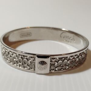 Coach silver-tone signature C logo embossed bangle bracelet. 